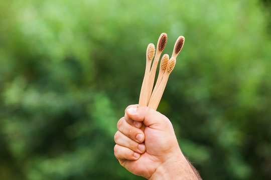 Hand with bamboo toothbrushes outdoor on nature
