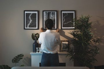 Woman arranging paintings at home