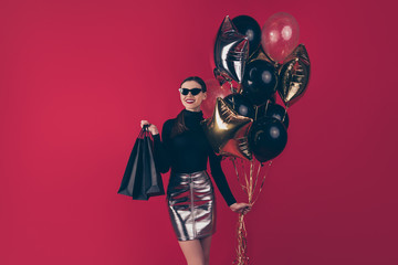 Portrait of her she nice-looking attractive pretty trendy cheerful cheery glad lady holding in hands black bags air balls clothes store isolated on maroon burgundy marsala red pastel color background