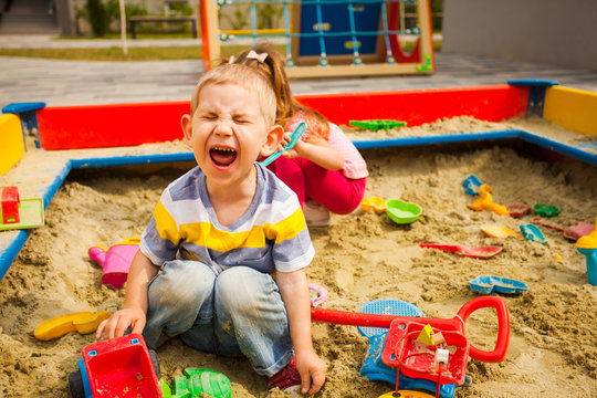 two grubby kids playing in the sandbox