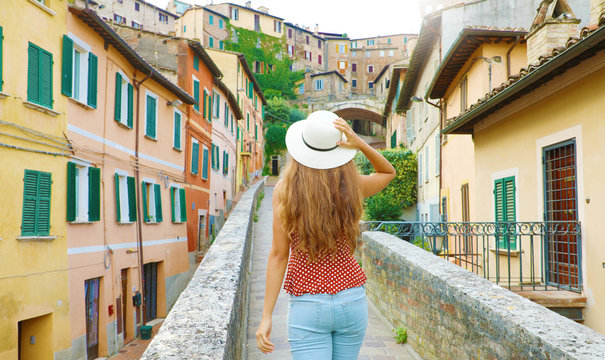 Discovering Italy. Back view of young attractive woman walking in old Italian city.