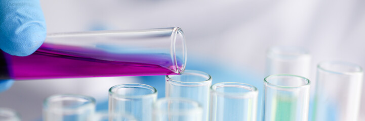 Male chemist holds test tube of glass in his hand overflows a liquid solution of potassium...