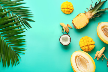 Sweet ripe fruits with tropical leaves on color background
