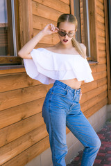Attractive young girl with a perfect figure and blond hair in trendy jeans and a white top with...