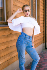 Attractive young girl with a perfect figure and blond hair in trendy jeans and a white top with...