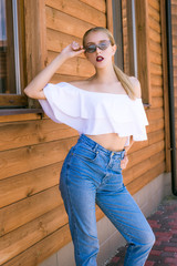 Attractive young girl with a perfect figure and blond hair in trendy jeans and a white top with...