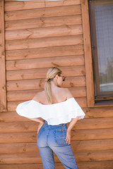 Attractive young girl with a perfect figure and blond hair in trendy jeans and a white top with...