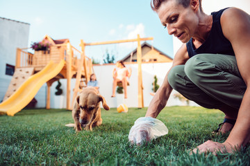 Woman picking up dog poop from the lawn