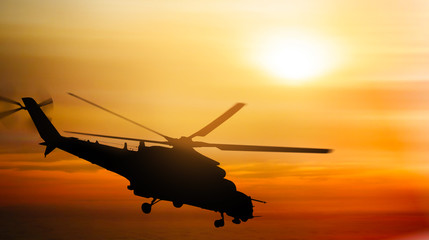 Helicopter silhouette flying in the sky at sunset