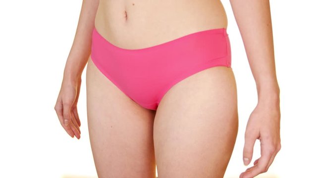 Close up of woman in pink lingerie covering crotch with her hands. White background.