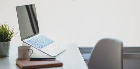 Open laptop computer with coffee cup and office supplies in comfortable workplace