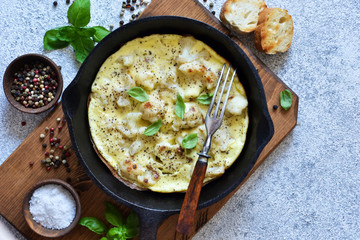 Omelet with vegetables in a pan on a concrete background. View from above.