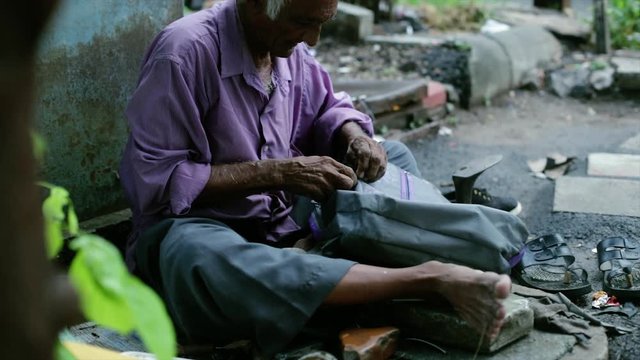 A cobbler repairing slippers of pilgrims by the roadside in the morning stock footage collection 6