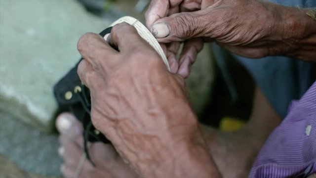 A cobbler repairing slippers of pilgrims by the roadside in the morning stock footage collection 14