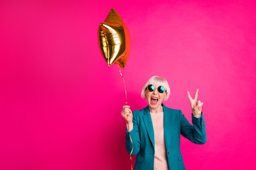 Portrait of her she nice-looking attractive crazy overjoyed cheerful cheery gray-haired lady holding balloon showing v-sign isolated on bright vivid shine vibrant pink fuchsia color background