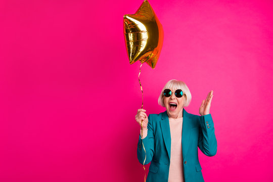 Portrait of her she nice-looking attractive lovely crazy overjoyed cheerful cheery gray-haired lady holding balloon having fun isolated on bright vivid shine vibrant pink fuchsia color background