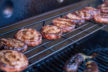 Barbecued beef burgers on a barbecue warming rack