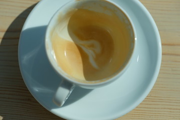 an empty cup of coffee stands on a wooden table