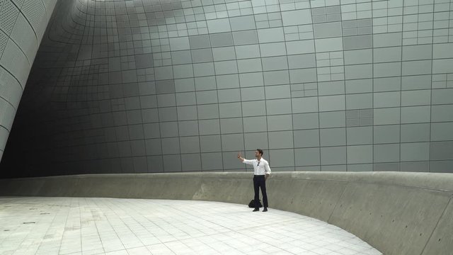 Male tourist takes a selfie on his phone at Dongdaemun Design Plaza in Seoul, Korea. Copy space.