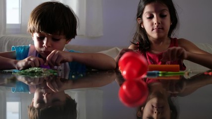 children play with plasticine figures at home while watching television