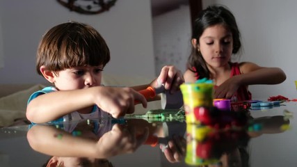 children play with plasticine figures at home while watching television