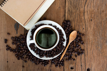 Roasted coffee beans Coffee cups and notebooks on old wooden floors.