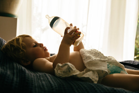 Kleiner Junge trinkt Milch aus einer Flasche