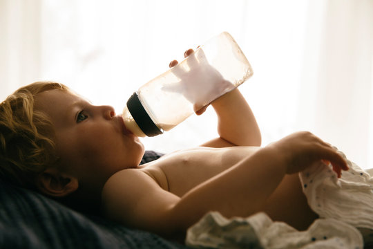 Kleiner Junge trinkt Milch aus einer Flasche