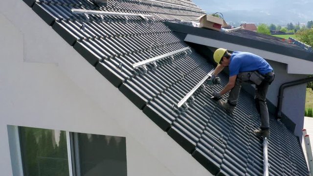 Two guys sutting up cables for solar panel installation on the roof on sunny Summer day in Slovenia
