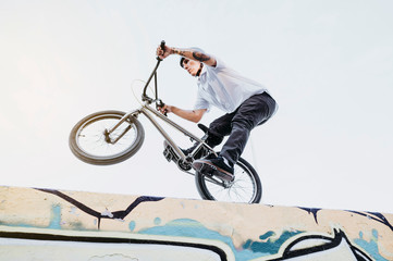 Fototapeta na wymiar Side view of man riding and balancing while performing trick on BMX in skatepark.