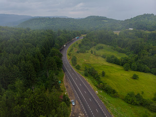 Fototapeta premium Aerial view over mountain road going through forest landscape. Transylvania, Romania