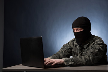Masked cyber terrorist in military uniform hacking army intelligence - obrazy, fototapety, plakaty