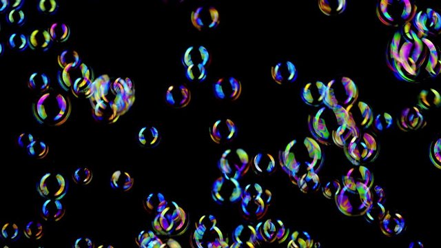 Colorful soap bubbles fly across black background.