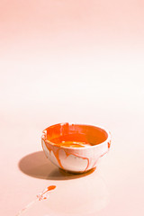 High angle composition with orange paint in bowl