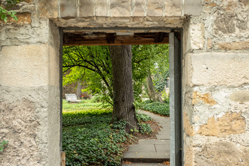 Steinerner Eingang mit Weg und Bäumen zu einem Park Fokus Hintergrund