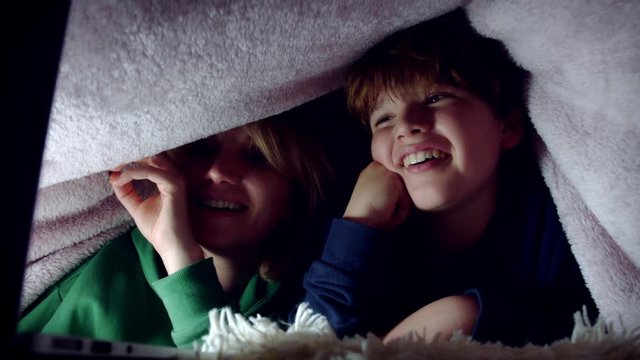 4K Dolly Shot of Mum and Son watching Movie under the Blanket