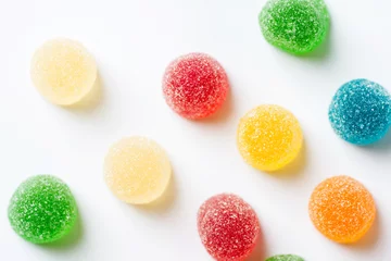 Tuinposter Colorful yellow red orange green gummy jelly candies coated with sugar on white background. Kids birthday party Halloween sweets fun concept. Creative minimalist food poster top view. Blurry © olindana