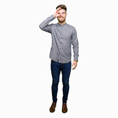 Fototapeta premium Young handsome business casual man doing ok gesture with hand smiling, eye looking through fingers with happy face.