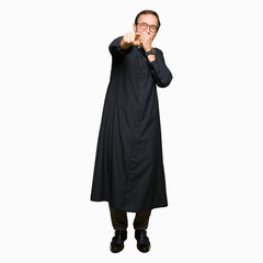 Middle age priest man wearing catholic robe Laughing of you, pointing to the camera with finger...