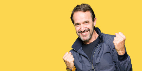 Middle age handsome man wearing a jacket very happy and excited doing winner gesture with arms...
