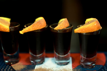 Alcohol shots on bar with tequila and oranges