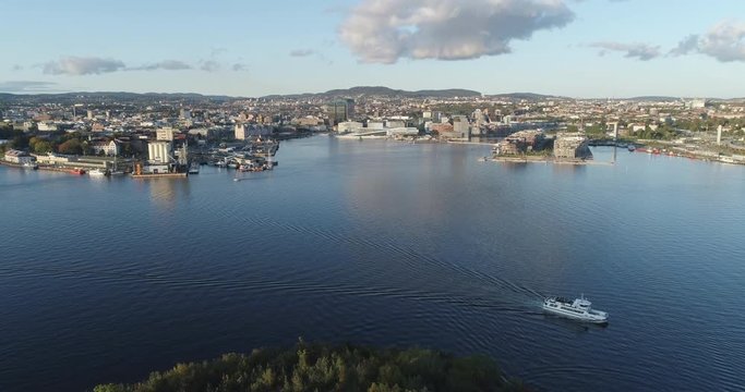 Cinema 4K drone shot with forward tilt reveal motion of Hoved&oslash;ya island, a ferry, the Oslofjord and the Bj&oslash;rvika project with the Lambda Munch Museum and Opera House in autumn fall, in Oslo Norway.