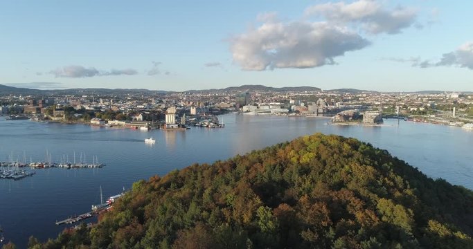 Cinema 4K drone shot with slide tilt reveal motion of Hoved&oslash;ya island, the blue Oslofjord and the Bj&oslash;rvika project with the Lambda Edvard Munch Museum and Opera House in autumn fall, in Oslo Norway.