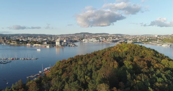 Cinema 4K drone shot with slide motion of Hoved&oslash;ya island, the blue Oslofjord and the Bj&oslash;rvika project with the Lambda Edvard Munch Museum and Oslo Opera House in autumn fall, in Oslo Norway.