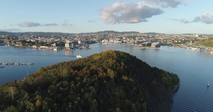 Cinema 4K drone shot with forward tilt reveal motion of Hoved&oslash;ya island, the blue Oslofjord and the Bj&oslash;rvika project with the Lambda Edvard Munch Museum and Opera House in autumn fall, in Oslo Norway.