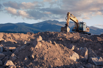 Excavator moving stone and earth - Powered by Adobe
