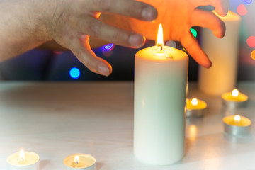 Hands drawn out above the burning candle. Burning candle symbol of eternity and remembrance of the...