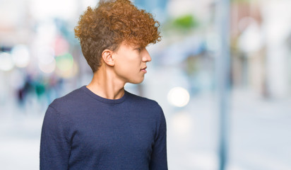 Fototapeta premium Young handsome man with afro hair looking away to side with smile on face, natural expression. Laughing confident.