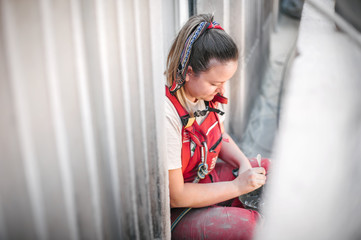 Female construction mason on the scaffolding, plastering and renovating building