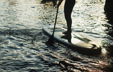 Stand up paddle surfing silhouette. a man stands with a paddle on a Board closeup, © vulkanov